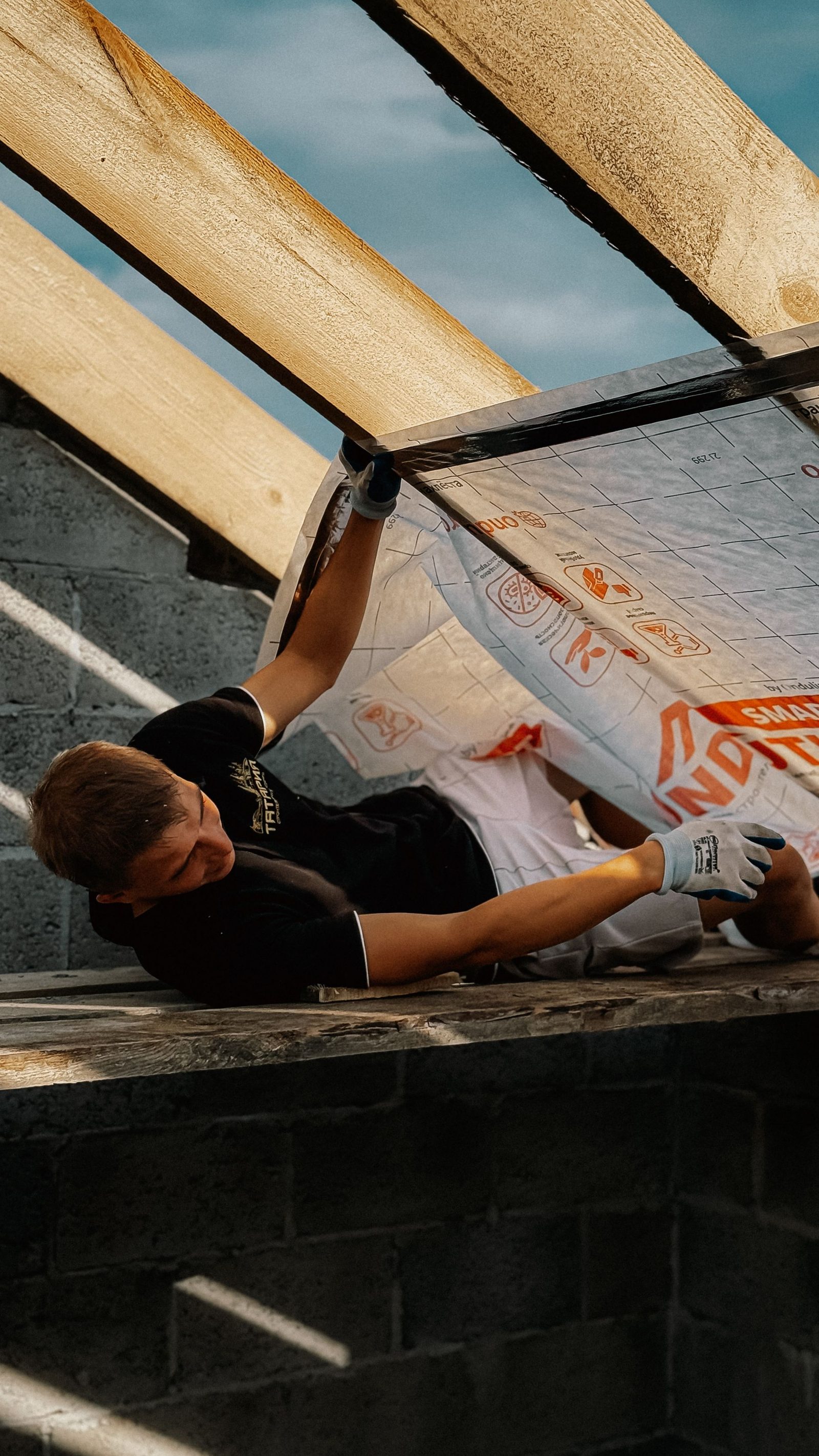 Installer fitting insulated roof panels on a roof structure